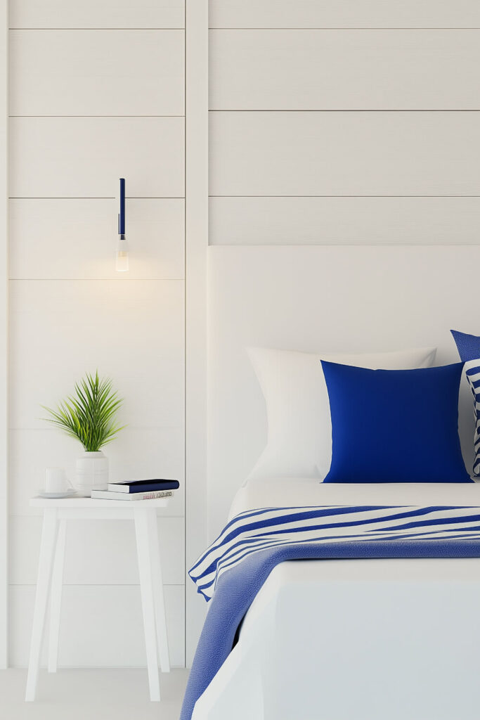 A modern coastal minimalist bedroom features white shiplap walls, navy blue accents, and simple white furniture.